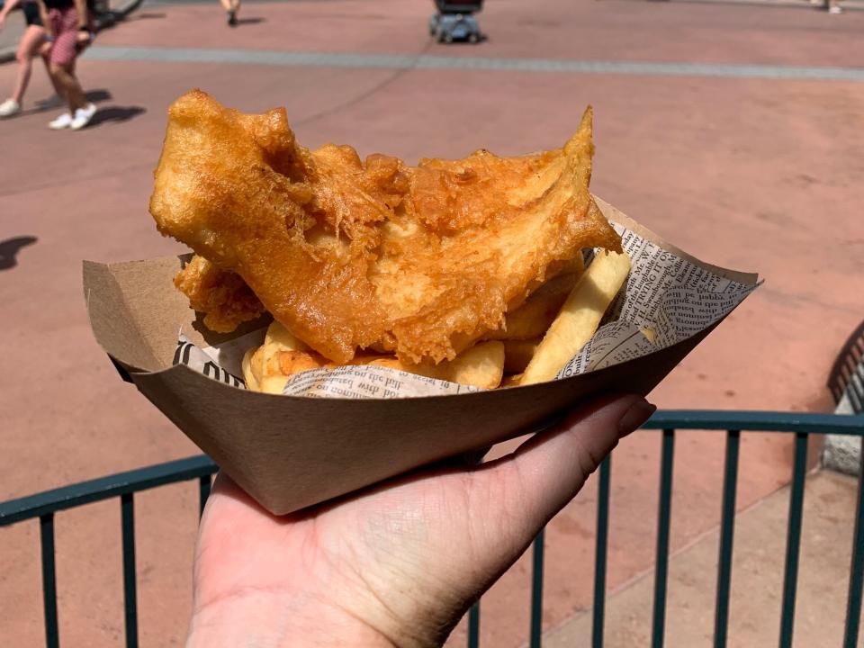 hand holding basket of fish and chips in the uk pavilion at epcot