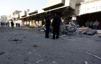 Iraqi policemen inspect the site of car bomb attack in Baghdad December 16, 2013. A series of suicide bombings and car and roadside bombs across Iraq killed at least 17 people on Monday, medical and police sources said. (REUTERS/Ahmed Saad)