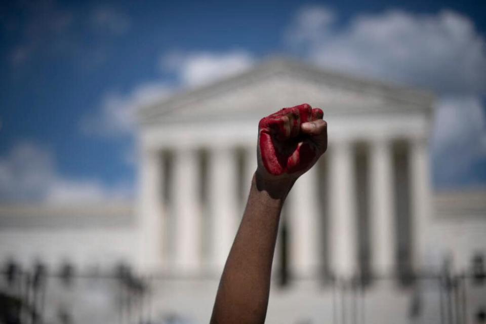 An abortion rights demonstrator raises a fist, painted in red, while yelling during a rally on June 25, 2022 in front of the U.S. Supreme Court in Washington, a day after the court released a decision on Dobbs v. Jackson Women’s Health Organization, striking down the constitutional right to an abortion. (Photo by ROBERTO SCHMIDT/AFP via Getty Images)