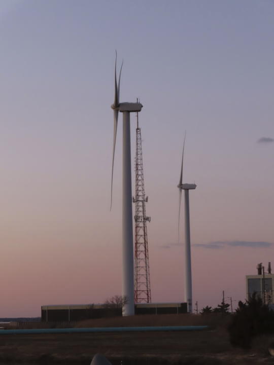 The sun sets behind a land-based wind farm in Atlantic City, N.J. on Feb. 10, 2022. On Monday, March 6, 2023, New Jersey utility regulators issued a solicitation for additional offshore wind energy projects beyond the three already approved by the state. (AP Photo/Wayne Parry)