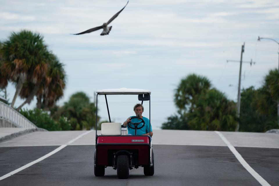 A resident drives his golf car over a bridge on Cedar Key, Fla., ahead of the expected arrival of Hurricane Idalia, Tuesday, Aug. 29, 2023. (AP Photo/Rebecca Blackwell)