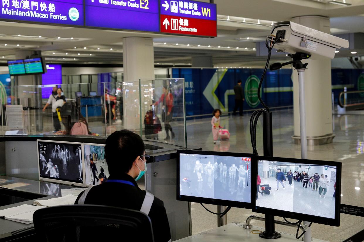 FILE - In this Jan. 4, 2020, file photo, a health surveillance officer monitors passengers arriving at the Hong Kong International airport in Hong Kong. On Friday, Jan. 17, 2020, the U.S. Centers for Disease Control and Prevention officials said they will begin screening airline passengers at three U.S. airports who traveled from Wuhan in central China, for a new illness that has prompted worries about a new international outbreak. (AP Photo/Andy Wong, File)