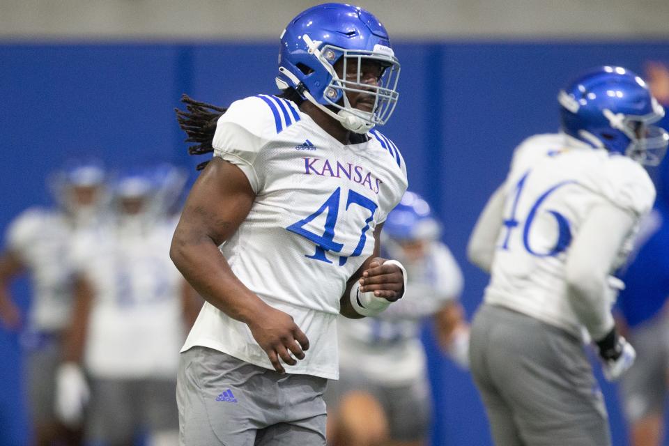 Kansas redshirt junior defensive end Lonnie Phelps (47) runs through drills during practice Friday evening at the indoor practice facility.