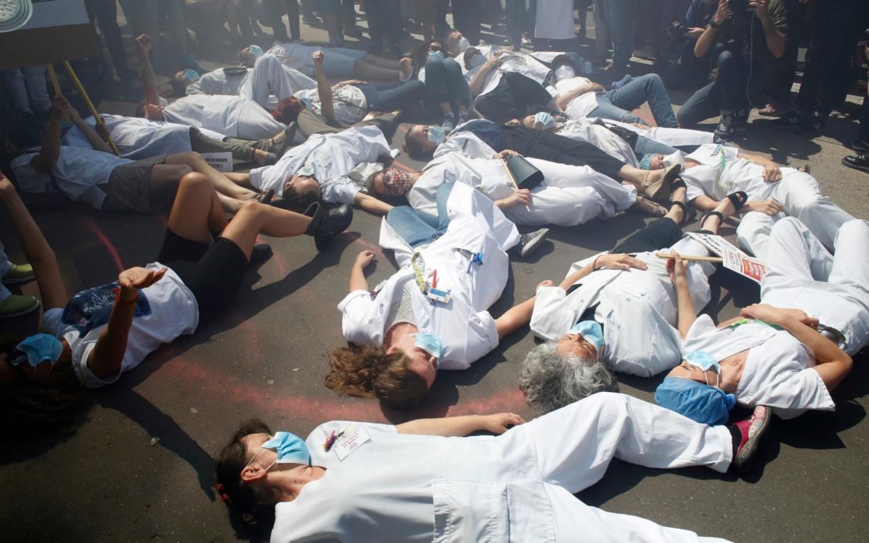 Medical staff lie down on the floor as they demonstrate at the Robert Debre hospital Thursday, May 28, 2020 in Paris - Thibault Camus /AP