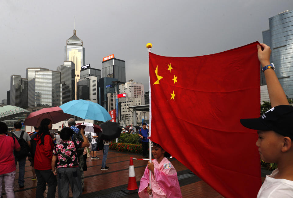 Pro-China supporters raise a China national flag during a counter-rally in support of the police in Hong Kong Saturday, July 20, 2019. Police in Hong Kong have raided a homemade-explosives manufacturing lab ahead of another weekend of protests in the semi-autonomous Chinese territory. (AP Photo/Vincent Yu)