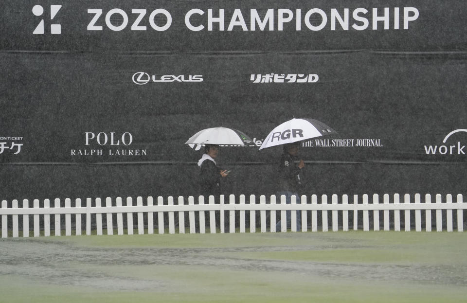 People hold umbrellas in the rain as they walk past near the practice area after the second round of the Zozo Championship PGA Tour is postponed due to heavy rain at the Accordia Golf Narashino country club in Inzai, east of Tokyo, Japan, Friday, Oct. 25, 2019. (AP Photo/Lee Jin-man)
