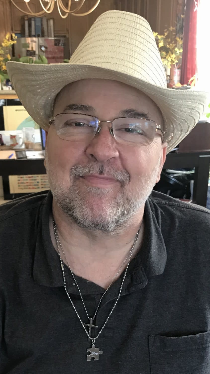 David Paul Harris smiles while wearing glasses and a straw hat in a family photo