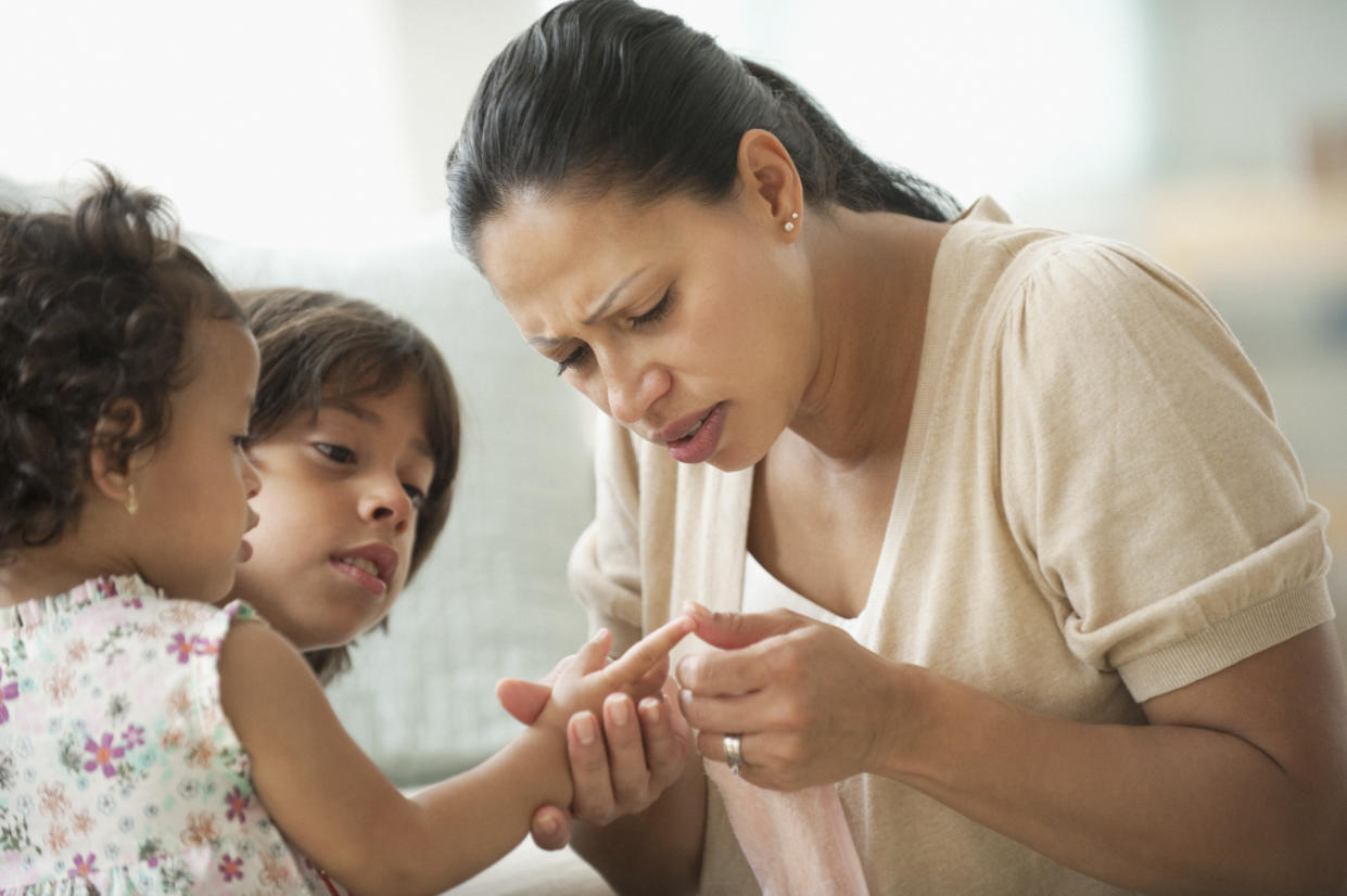 A concerned. mother checks her daughter's injury.