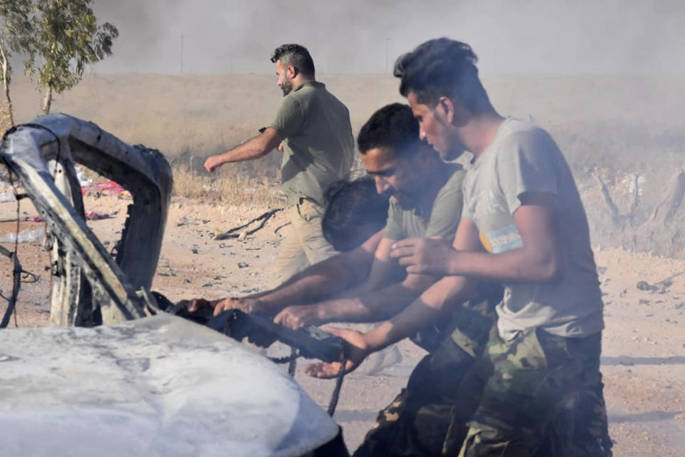 FILE - In this Sunday, Aug. 25, 2019 file photo, Popular Mobilization Forces members try to get a body out of a car after a drone attack near the Qaim border crossing, in Anbar province, Iraq. The long shadow war between Israel and Iran has burst into the open in recent days, with Israel allegedly striking Iran-linked targets as far away as Iraq and crash-landing two drones in Lebanon. These incidents, along with an air raid in Syria that Israel says thwarted an imminent Iranian drone attack, have raised tensions at a particularly fraught time. (AP Photo, File)
