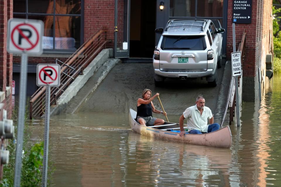 Jodi Kelly, left, practice manager at Stonecliff Veterinary Surgical Center, behind, and her husband, veterinarian Dan Kelly, use a canoe to remove surgical supplies from the flood-damaged center, Tuesday, July 11, 2023, in Montpelier, Vt.