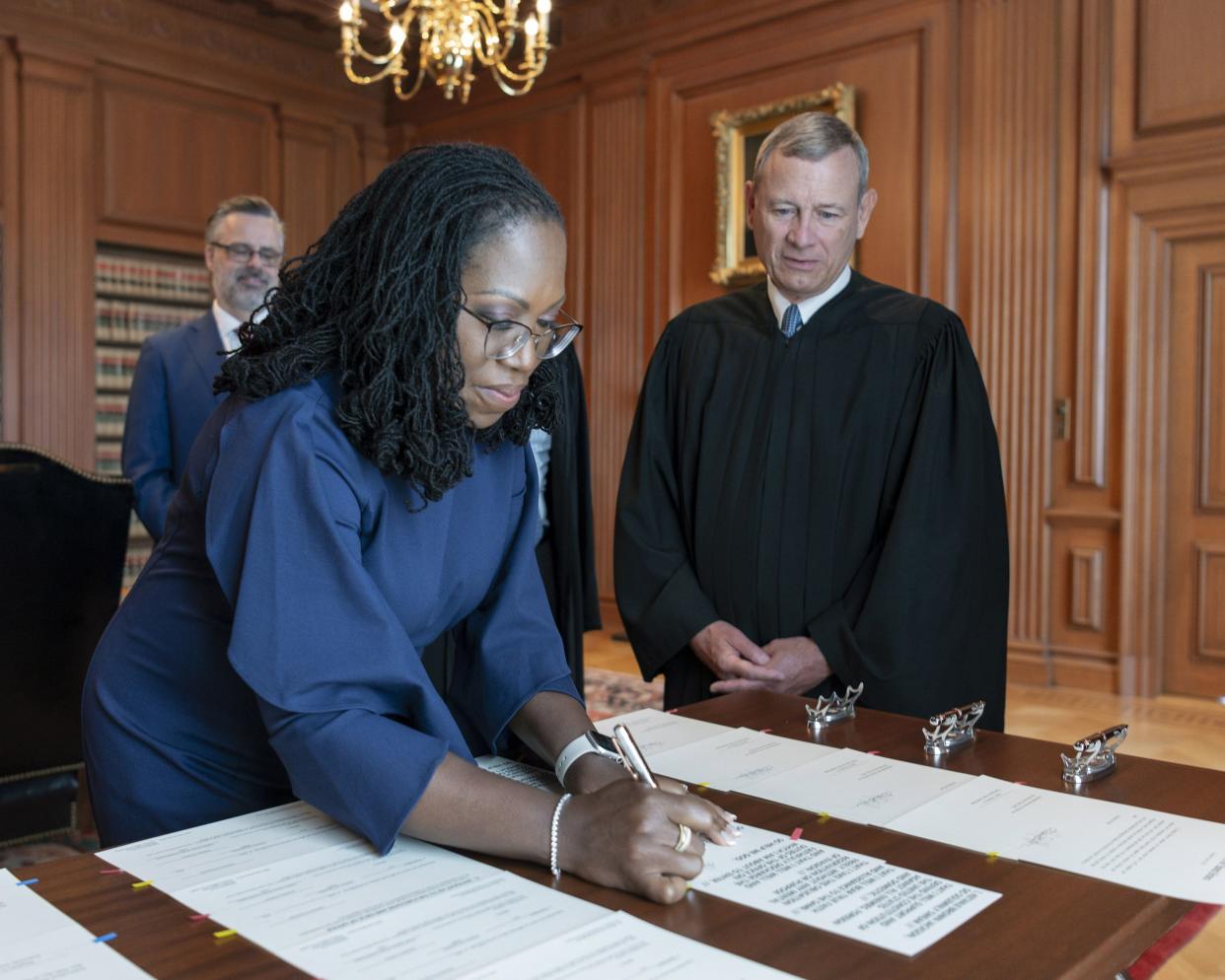 In this image provided by the Collection of the Supreme Court of the United States, Supreme Court Justice Ketanji Brown Jackson signs the Oaths of Office at the Supreme Court in Washington, Thursday, June 30, 2022, as Chief Justice of the United States John Roberts watches. 