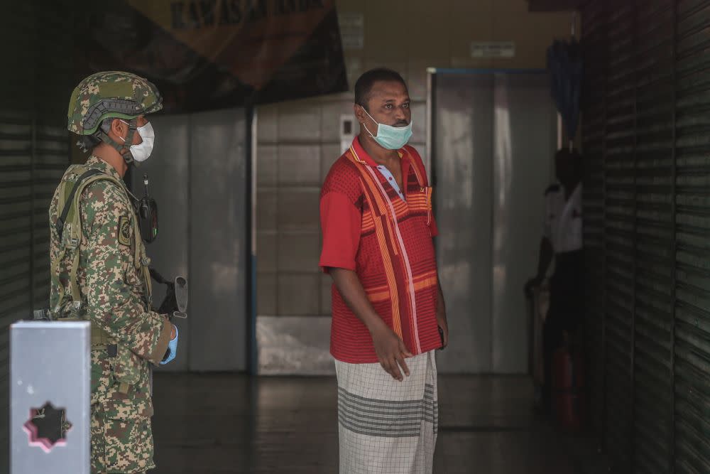 A Selangor Mansion resident looks on as Armed Forces personnel cordon off the vicinity with barbed wire on Jalan Masjid India April 7, 2020. — Picture by Firdaus Latif