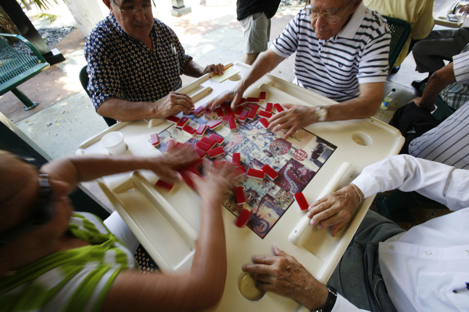 FILE - This Aug. 5, 2009 file photo shows domino players at play shuffling dominos at Maximo Gomez Park, also known as Domino Park, in the Little Havana neighborhood of Miami. Watching the domino game players compete is exciting for visitors to the park, along with walking through historic Little Havana. These activities are among some of the free cultural things that you can do and see in Miami. (AP Photo/Wilfredo Lee, File)
