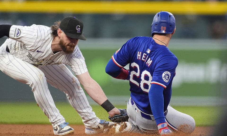 Colorado Rockies second baseman Brendan Rodgers, left, tags out Texas Rangers' Jonah Heim, right, at second base as Heim was trying to stretch a singgle into a double in the sixth inning of a baseball game Friday, May 10, 2024, in Denver. (AP Photo/David Zalubowski)