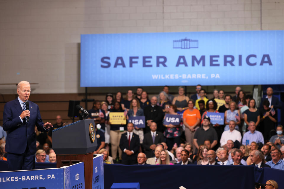 President Biden with a microphone and a poster saying Safer America, Wilkes-Barre, Pa., behind him.