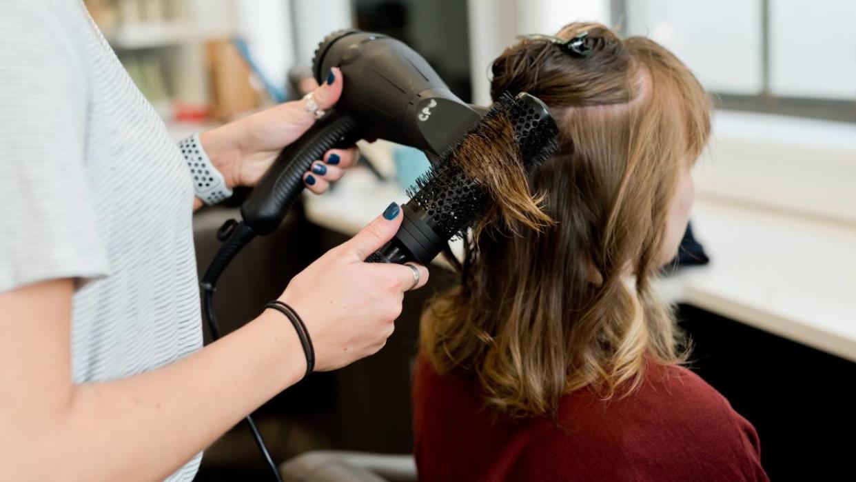  Woman getting her hair blow dried in a salon. 