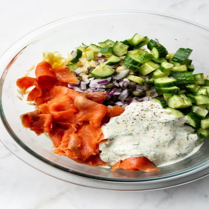 Cucumber, smoked salmon, capers, and yogurt sauce in a bowl.