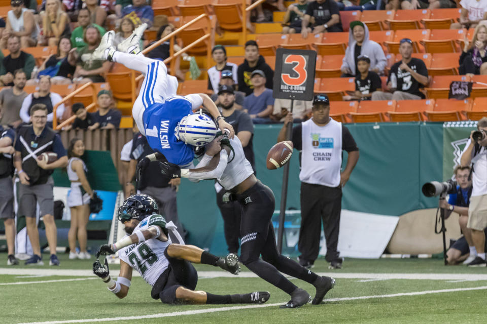 BYU quarterback Zach Wilson (1) loses the football on a hit by Hawaii defensive back Eugene Ford, right, as Wilson tried to leap into the end zone during the second half of the Hawaii Bowl NCAA college football game Tuesday, Dec. 24, 2019, in Honolulu. Hawaii recovered the football in the end zone for a touchback. (AP Photo/Eugene Tanner)