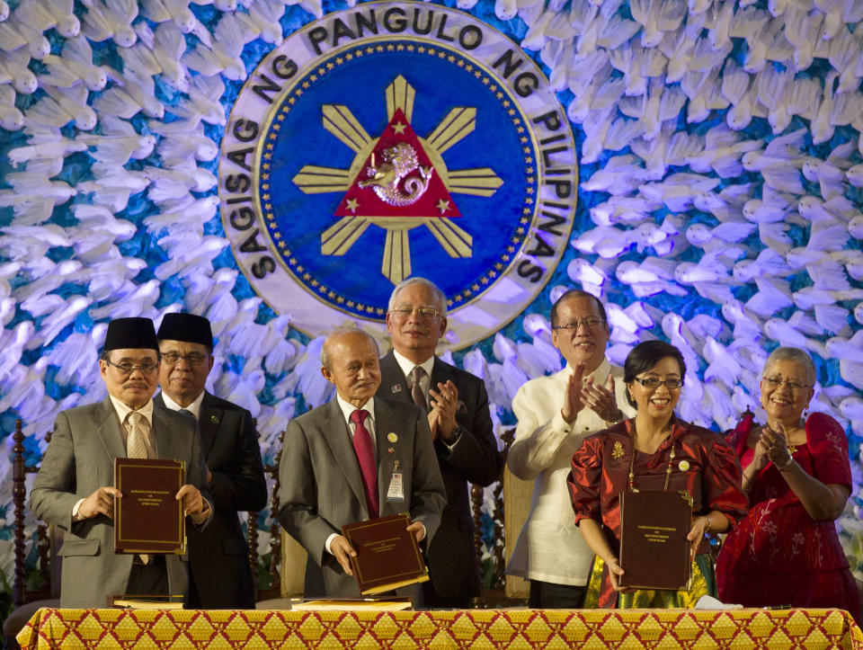 In this handout photo released by the Malacanang Photo Bureau, President Benigno S. Aquino III, third from right, applauds with Moro Islamic Liberation Front (MILF) Chairman, Al Haj Murad Ebrahim, second from left, Malaysian Prime Minister Najib Razak, center, and Secretary Teresita Quintos-Deles, Presidential Adviser on the Peace Process, right, after the signing of the Comprehensive Agreement on the Bangsamoro (CAB) by MILF chief negotiator Mohagher Iqbal, left, Datu Tengku Gnafar, third from left, and Miriam Coronel Ferrer, second from right, of the Philippine government in a ceremony at the Malacanang Presidential Palace in Manila, Philippines Thursday March 27, 2014. The Philippine government signed a peace accord with the country's largest Muslim rebel group on Thursday, the culmination of years of negotiations and a significant political achievement for President Aquino.(AP Photo/Malacanang Photo Bureau, Ryan Lim)