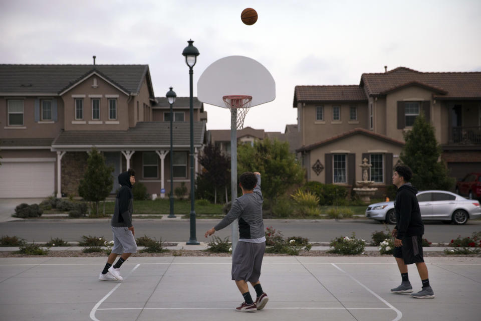 In this Monday, Sept. 3, 2018, photo, three men play basketball at a park in front of newly built homes in Salinas, Calif. Salinas is an affordable location compared to Silicon Valley, where median home prices are about $1 million, but with a less-wealthy population and a median home price that has ballooned to about $550,000 it's one of the least affordable places in America. (AP Photo/Jae C. Hong)