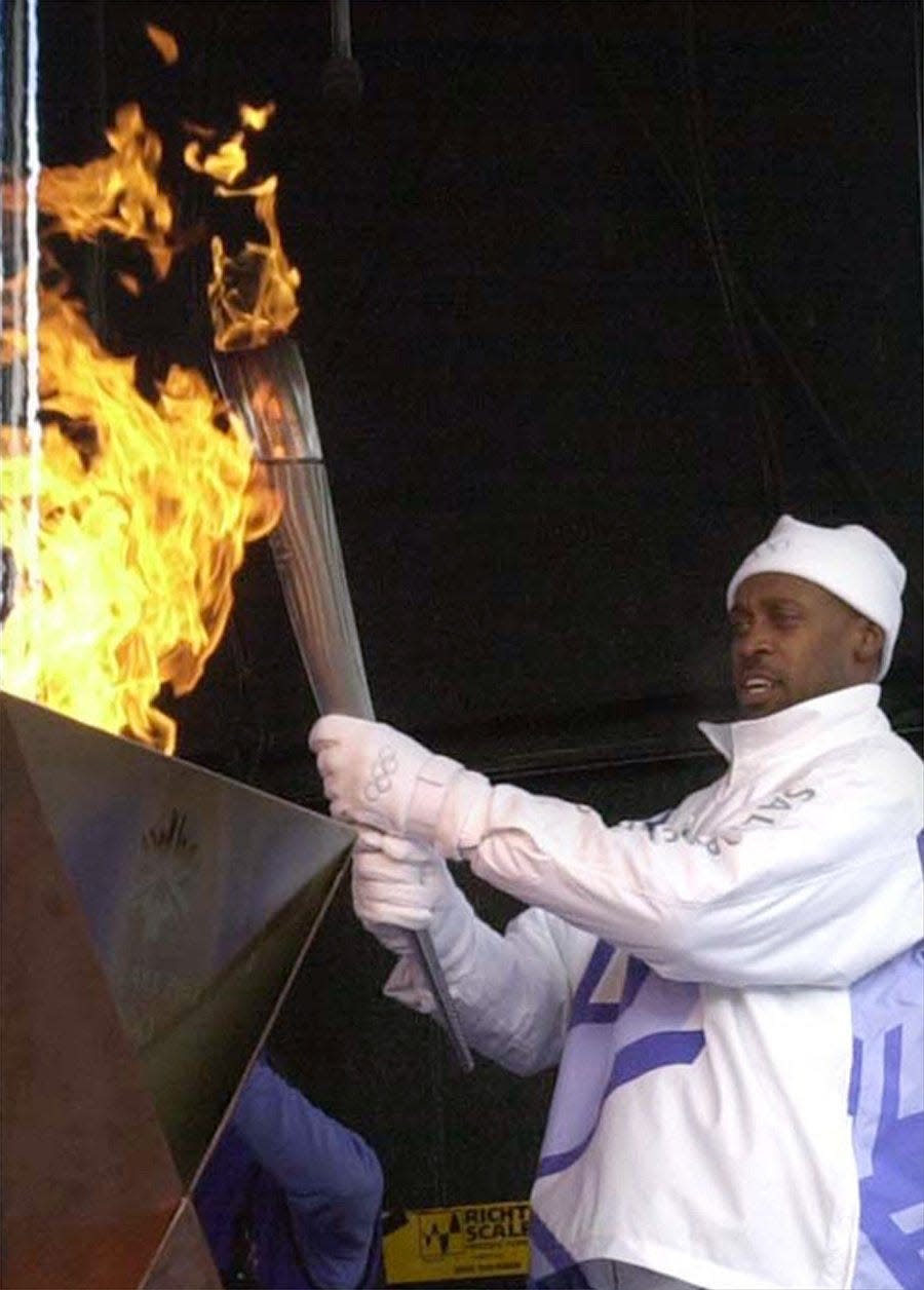 Olympian Butch Reynolds runs the last leg of the torch relay and lights the cauldren at Canal Park for the arrival of Olympic Torch in Downtown Akron on Jan. 2, 2002.