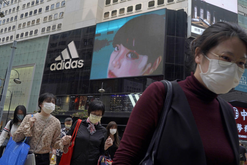 People walk past an Adidas sportswear store in Hong Kong, Saturday, March 27, 2021. H&M disappeared from the internet in China as the government raised pressure on shoe and clothing brands and announced sanctions Friday, March 26, 2021, against British officials in a spiraling fight over complaints of abuses in the Xinjiang region. Shockwaves spread to other brands as dozens of celebrities called off endorsement deals with Nike, Adidas, Burberry, Uniqlo and Lacoste after state media criticized the brands for expressing concern about Xinjiang. (AP Photo/Kin Cheung)