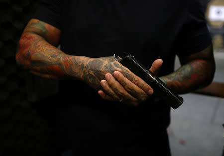 A member of the Colt 45 shooting club poses holding a gun in Rio de Janeiro, Brazil January 15, 2019. REUTERS/Pilar Olivares