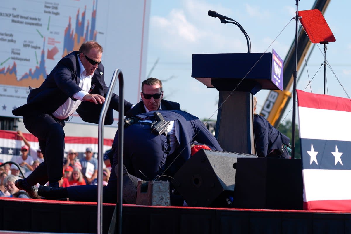 Secret Service agents rush to cover Republican presidential candidate Donald Trump at a campaign rally, Saturday, July 13, 2024 after shots were fired (AP)