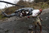 Villagers carry sacks of relief aid as a U.S. helicopter delivers aid to a remote village off Guiuan, Eastern Samar, in central Philippines November 20, 2013. The Philippines is facing an enormous rebuilding task from Typhoon Haiyan, which killed at least 3,974 people and left 1,186 missing, with many isolated communities yet to receive significant aid despite a massive international relief effort. REUTERS/Edgar Su (PHILIPPINES)