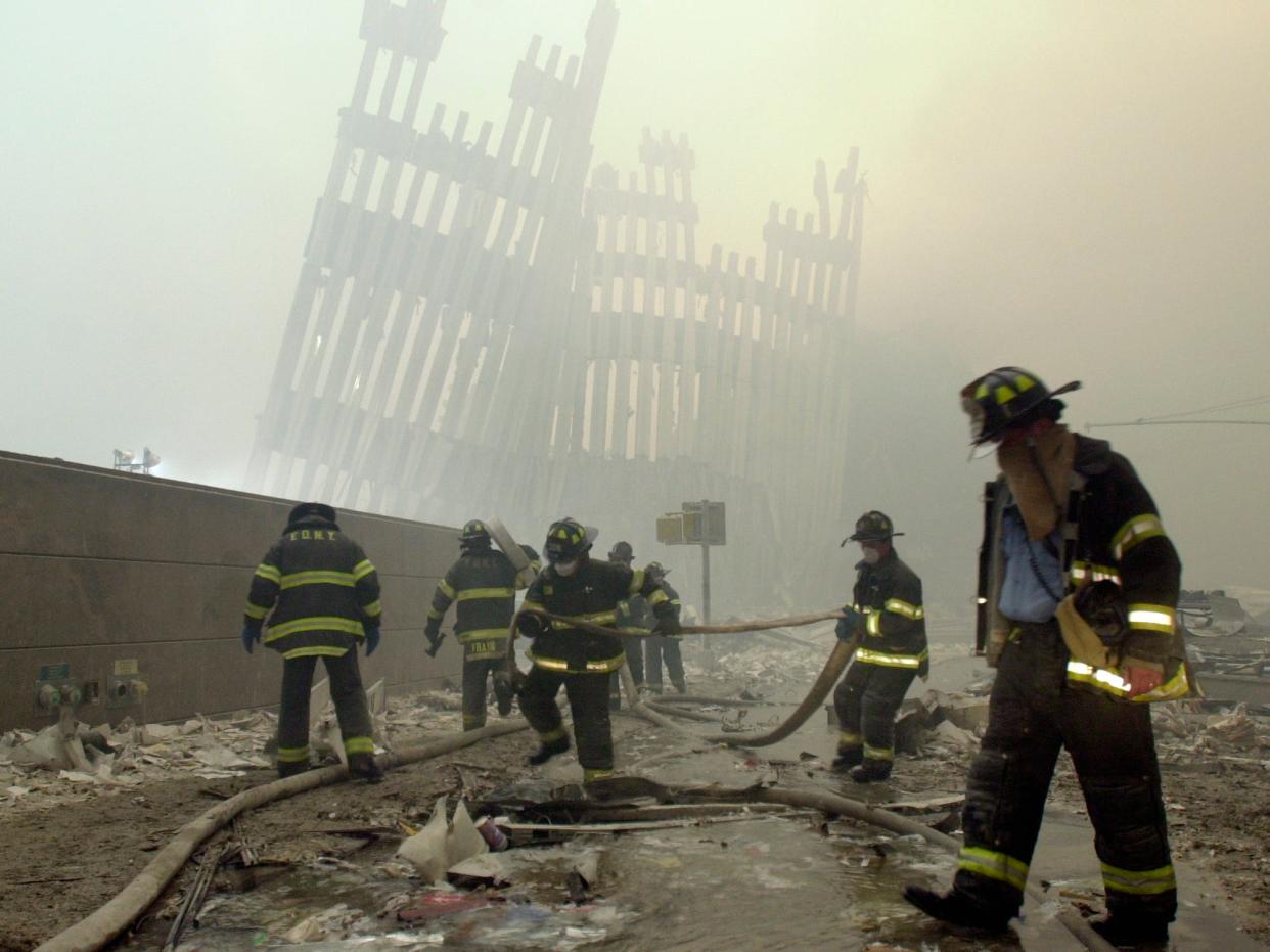 Firefighters work beneath the destroyed mullions, the vertical struts which once faced the soaring outer walls of the World Trade Center towers, in New York on Sept. 11, 2001.