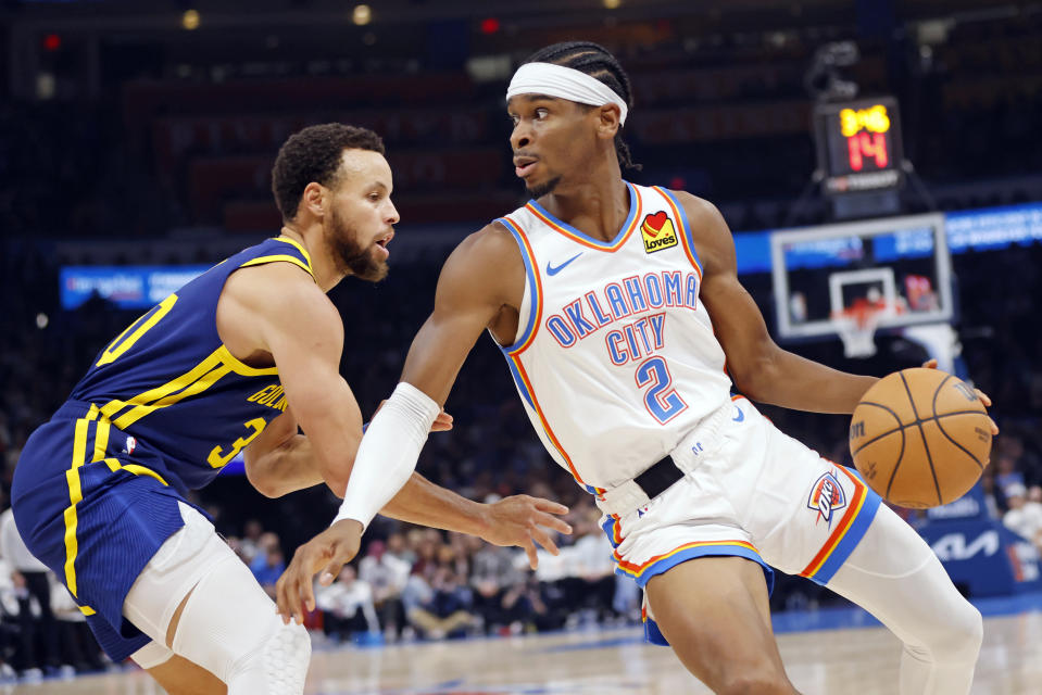 Oklahoma City Thunder guard Shai Gilgeous-Alexander (2) spins around Golden State Warriors guard Stephen Curry during the first half of an NBA basketball game Friday, Dec. 8, 2023, in Oklahoma City. (AP Photo/Nate Billings)