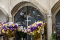 FILE - In this Saturday, April 18, 2020 file photo, a woman stands next to her husband, left, and her brother, right, as they attend the funeral of their mother who died of coronavirus at the Poble Nou cemetery in Barcelona, Spain. European Union leaders are preparing for a new virtual summit, which will take place Thursday, April 23, 2020, to take stock of the damage the coronavirus has inflicted on the lives and livelihoods of the bloc's citizens and to thrash out a more robust plan to revive their ravaged economies. (AP Photo/Emilio Morenatti, File)