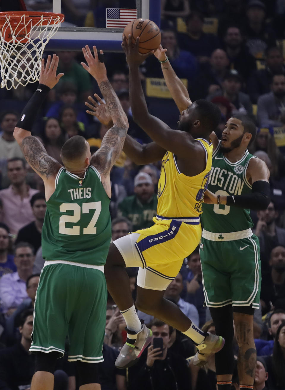 Golden State Warriors' Eric Paschall, center, shoots between Boston Celtics' Daniel Theis (27) and Jayson Tatum during the first half of an NBA basketball game Friday, Nov. 15, 2019, in San Francisco. (AP Photo/Ben Margot)