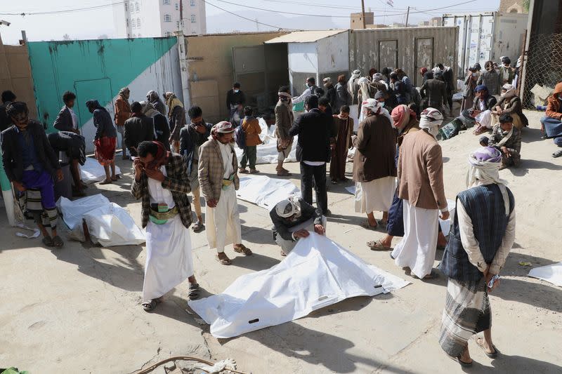 Relatives of victims inspect bodies of people killed by air strikes that hit a detention center in Saada