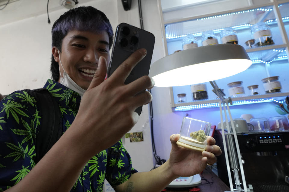 A customer talks on his mobile phone as he buys marijuana at the Highland Cafe in Bangkok, Thailand, Thursday, June 9, 2022. Measures to legalize cannabis became effective Thursday, paving the way for medical and personal use of all parts of cannabis plants, including flowers and seeds. (AP Photo/Sakchai Lalit)