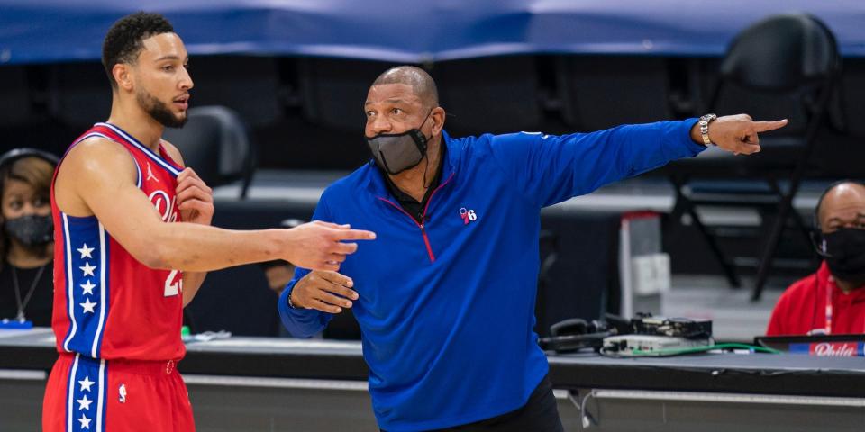 Ben Simmons stands next to Doc Rivers as Rivers points on the court.