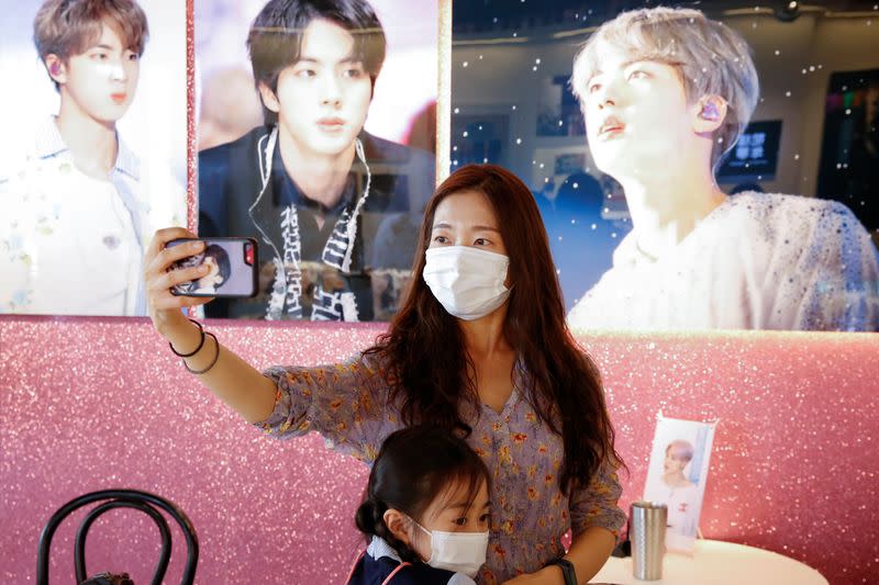 Kang Lucia, fan of K-pop boy band BTS, takes a selfie at a cafe decorated with photos and merchandise of them, in Seoul