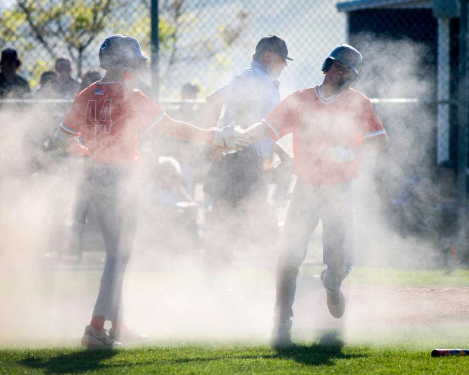 Damon Mitchell, left, shakes hands in a cloud of dust kicked up by Drew Cappel who scored in a slide home. Atascadero won 8-3 over San Luis Obispo in a baseball game May 3, 2024. David Middlecamp/dmiddlecamp@thetribunenews.com