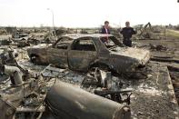 Prime Minister Justin Trudeau, left, and Fort McMurray Fire Chief Darby Allen look over a burnt out car during a visit to Fort McMurray, Alta., on Friday, May 13, 2016. THE CANADIAN PRESS/Jason Franson