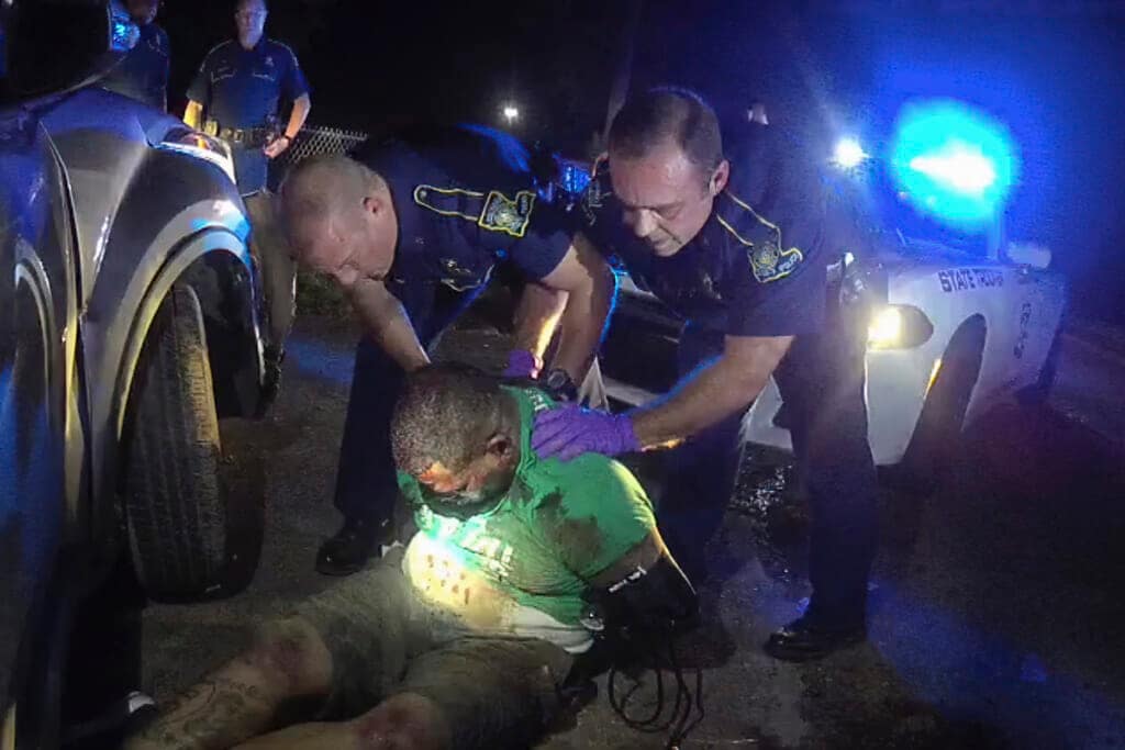 This image from the body camera video of Louisiana State Police Trooper Dakota DeMoss shows his colleagues, Kory York, center left, and Chris Hollingsworth, center right, holding up Ronald Greene before paramedics arrived on May 10, 2019, outside of Monroe, La. (Louisiana State Police via AP, File)