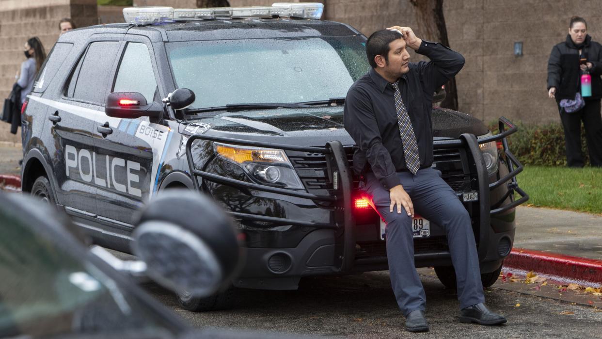 Eric Balderas, an employee at a department store in the mall, rests on a police vehicle after falling while evacuating the mall.