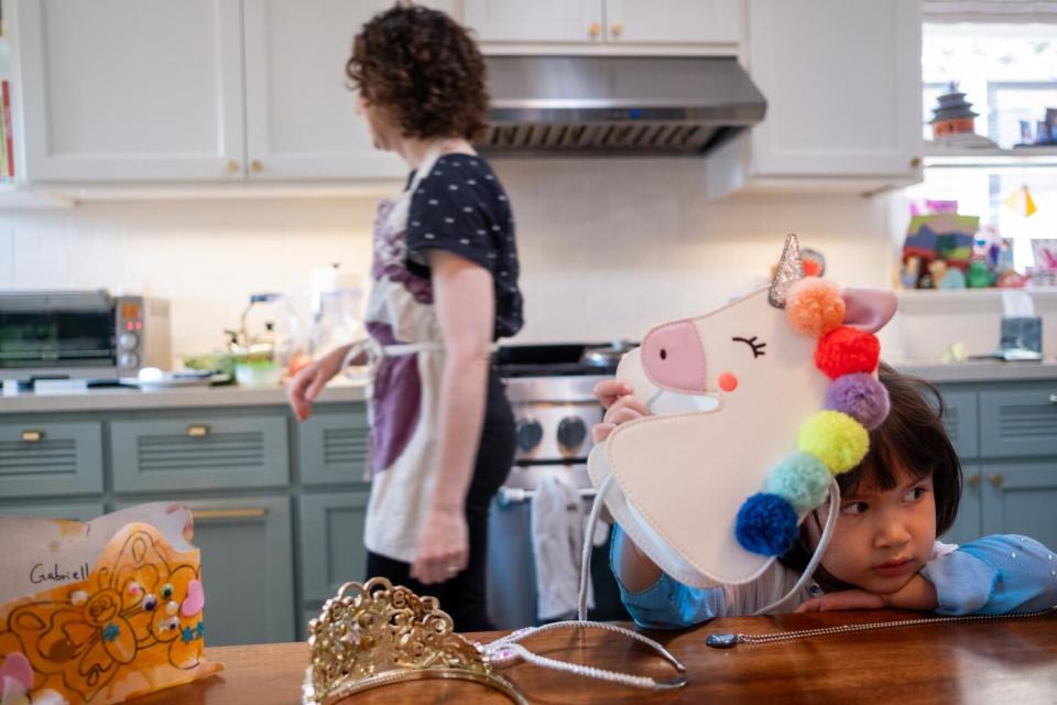 Elana Mann cooks dinner for her family as her daughter, Gabriella Mann-Leonard, 3, plays in the kitchen.