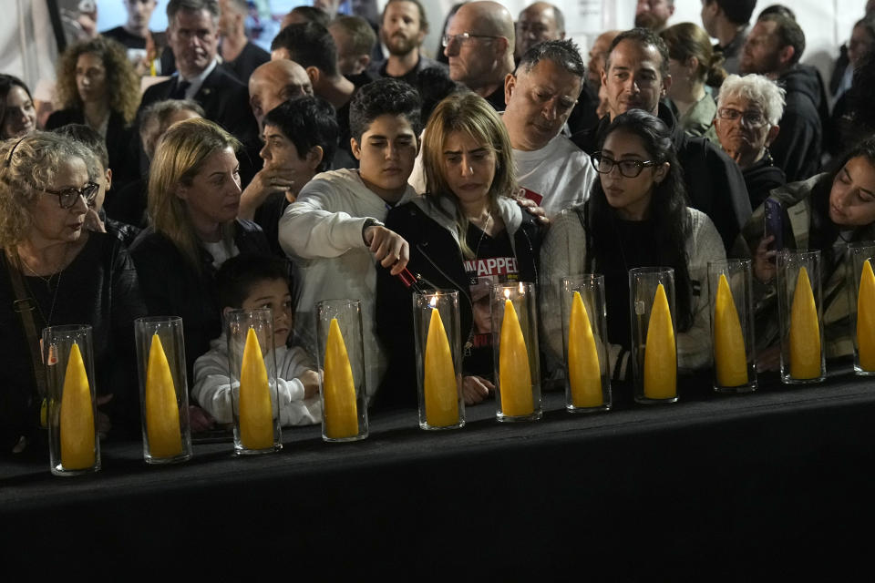 A boy lights a Hanukkah candle as relatives and friends of hostages held in the Gaza Strip by the Hamas militant group call for their release during the Jewish holiday of Hanukkah in the Hostages Square at the Museum of Art in Tel Aviv, Israel, Thursday, Dec. 7, 2023. (AP Photo/Ariel Schalit)