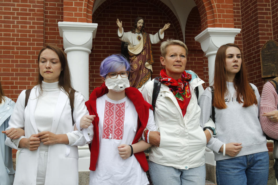 Protesters stand in front of the Church of Saints Simon and Helena during a rally in Minsk, Belarus, Thursday, Aug. 27, 2020. Russian President Vladimir Putin warned that he stands ready to send police to Belarus if protests there turn violent, but added in an interview broadcast Thursday that there is no such need now and voiced hope for stabilizing the situation in the neighboring country. (AP Photo/Dmitri Lovetsky)