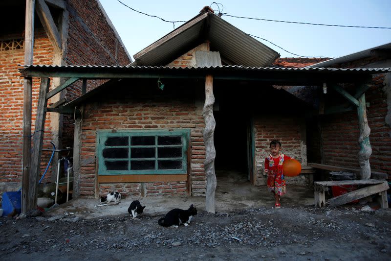 Aisyah Ayu, a 4-year-old girl, plays near a house affected by land subsidence at Tambaklorok village in Semarang