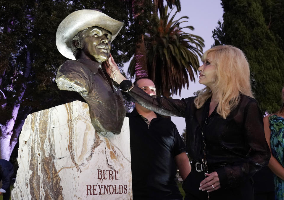 La actriz Loni Anderson, exesposa del difunto actor Burt Reynolds, toca un busto de bronce durante la ceremonia de su develación en el cementerio Hollywood Forever, en Los Ángeles, el lunes 20 de septiembre de 2021. Reynolds murió en 2018 a los 82 años. (AP Foto/Chris Pizzello)