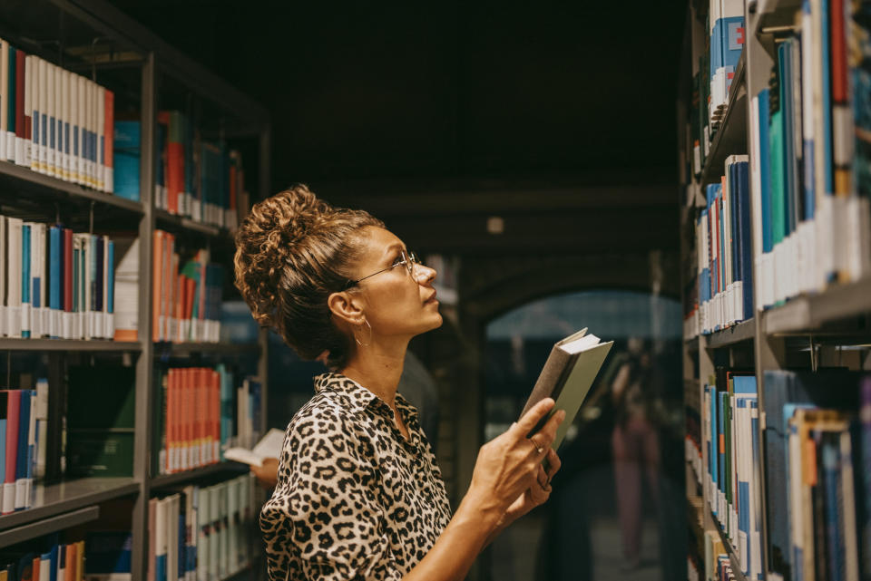 A woman is looking for a book in the library