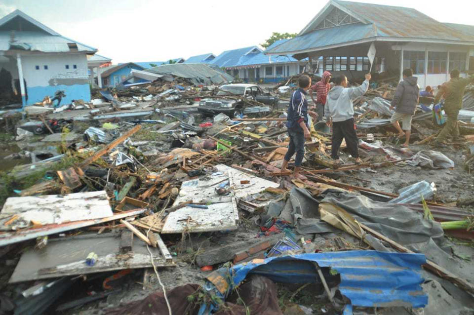 People survey the damage following a massive earthquake and tsunami in Palu, Central Sulawesi, Indonesia, Sunday, Sept. 30, 2018. Rescuers were scrambling Sunday to try to find trapped victims in collapsed buildings where voices could be heard screaming for help after a massive earthquake in Indonesia spawned a deadly tsunami two days ago. (AP Photo/Rifki)