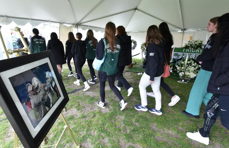 Student athletes pay their respects at the casket for their principal and football coach Paul Funk during his wake at the Dennis-Yarmouth High School on Saturday morning.