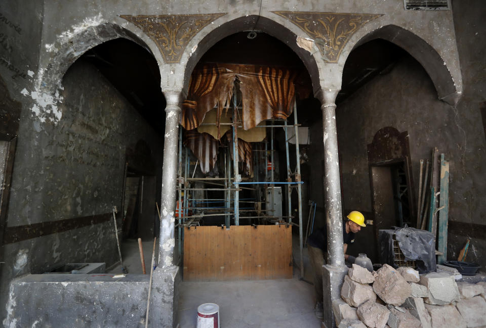 A worker works inside a heritage house that was damaged by Aug. 4 explosion that hit the seaport of Beirut, as part of it hold by scaffolding, in Beirut, Lebanon, Tuesday Aug. 25, 2020. In the streets of Beirut historic neighborhoods, workers are erecting scaffolding to support buildings that have stood for more than a century - now at risk of collapse after the massive Aug. 4 explosion that tore through the capital. (AP Photo/Hussein Malla)